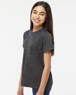 Load image into Gallery viewer, Three-quarter side angle of a young model wearing the Black Leopard t-shirt, highlighting the sleeve length and subtle animal print pattern."
