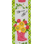Load image into Gallery viewer, Close-up front view of the Gardening Posie ribbon highlighting the crisp white fabric, a red dotted boot bouquet filled with sunflowers, illustrated gardening tools, and the wired plaid edge.
