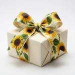 Load image into Gallery viewer, A crisp cream gift box tied with a large, beautifully structured bow crafted from the Sunflowers Spray ribbon, showcasing its shape retention.
